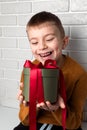 Beautiful boy in a yellow sweater holds a green round gift with a red ribbon Royalty Free Stock Photo