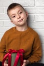 Beautiful boy in a yellow sweater holds a green round gift with a red ribbon Royalty Free Stock Photo