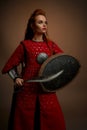 Brave woman in medieval tunic posing with weapon.