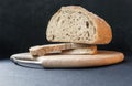 Beautiful bread made from rye and wheat flour on a wooden board on a black background. Sliced slices and half bread. Royalty Free Stock Photo