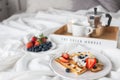 Beautiful breakfast in bed: Viennese Belgian waffles decorated with berries, a plate with strawberries and blueberries