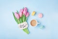 Beautiful breakfast on Mothers or Womans day. Coffee cup with pink tulip flowers, macaroon and note good morning on blue table.