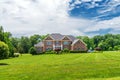 Beautiful brick country house in the suburbs of Leesburg, Virginia with trees and a spacious green lawn in the foreground