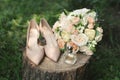 Beautiful bridal bouquet of white roses on a wooden stump. Stylish, leather shoes bride beige. Wedding in vintage style.