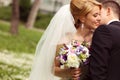 Beautiful bridal couple having fun in the park on their wedding day flower bouquet Royalty Free Stock Photo