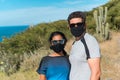 A beautiful bridal couple with a protective mask on the hillside. The bride and groom in the mountains