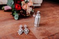 Beautiful bridal earrings and perfume on the wooden floor next to the wedding bouquet