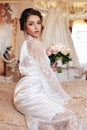 Beautiful bride with blond hair in elegant lace robe having morning preparation in wedding day