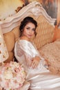 Beautiful bride with blond hair in elegant lace robe having morning preparation in wedding day