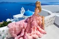 Beautiful bride blonde female model in amazing wedding dress poses on the island of Santorini in Greece Royalty Free Stock Photo