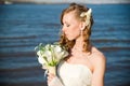 Beautiful bride with a bouquet of calla lilies on coast of river