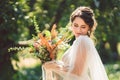 Beautiful bride with bouquet flowers stands on forest background. Rustic style. beautiful bride in delicate dress outdoors. Close Royalty Free Stock Photo