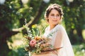 Beautiful bride with bouquet flowers stands on forest background. Rustic style. beautiful bride in delicate dress outdoors. Close Royalty Free Stock Photo