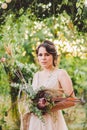 Beautiful bride with bouquet flowers stands on forest background. Rustic style. beautiful bride in delicate dress outdoors. Close Royalty Free Stock Photo