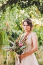 Beautiful bride with bouquet flowers stands on forest background. Rustic style. beautiful bride in delicate dress outdoors. Close Royalty Free Stock Photo