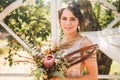 Beautiful bride with bouquet flowers stands on forest background. Rustic style. beautiful bride in delicate dress outdoors. Close Royalty Free Stock Photo