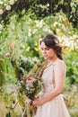 Beautiful bride with bouquet flowers stands on forest background. Rustic style. beautiful bride in delicate dress outdoors. Close Royalty Free Stock Photo