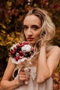 Beautiful bride with a bouquet in her hands. Wedding in autumn in the forest