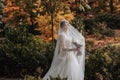 Beautiful bride with closed eyes, standing in an autumn park, holding her bouquet. Royalty Free Stock Photo