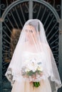 beautiful bride covered with a veil with bridal bouquet