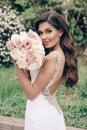 Beautiful bride with dark hair in luxurious wedding dress with tender wedding bouquet Royalty Free Stock Photo