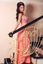 Beautiful bride in elegant coral dress posing on stairs