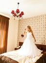 Beautiful bride with fashion veil posing on bed at wedding morning. Makeup. Blonde girl with long wavy hair styling Royalty Free Stock Photo