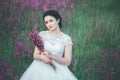 Beautiful bride in a flower field. The girl in a white dress with a bouquet in a summer field at sunset Royalty Free Stock Photo