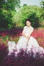 Beautiful bride in a flower field. The girl in a white dress with a bouquet in a summer field at sunset Royalty Free Stock Photo