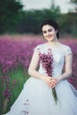 Beautiful bride in a flower field. The girl in a white dress with a bouquet in a summer field at sunset Royalty Free Stock Photo