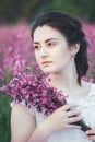 Beautiful bride in a flower field. The girl in a white dress with a bouquet in a summer field at sunset Royalty Free Stock Photo