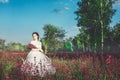 Beautiful bride in a flower field. The girl in a white dress with a bouquet in a summer field at sunset Royalty Free Stock Photo