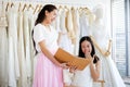 Beautiful bride getting dressed by her best friend in her wedding day and choosing a wedding dress in the shop and the shop Royalty Free Stock Photo