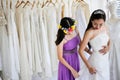 Beautiful bride getting dressed by her best friend in her wedding day and choosing a wedding dress in the shop and the shop Royalty Free Stock Photo