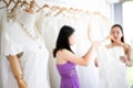 Beautiful bride getting dressed by her best friend in her wedding day and choosing a wedding dress in the shop and the shop Royalty Free Stock Photo