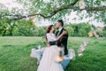 Beautiful bride and groom in evening park embracing under tree decorated with many lanterns Royalty Free Stock Photo