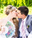 Beautiful bride and groom sitting in grass and kissing. Young wedding couple Royalty Free Stock Photo