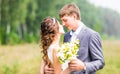 Beautiful bride and groom standing in grass and kissing. Wedding couple Royalty Free Stock Photo