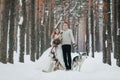 Beautiful bride and groom with two siberian husky are posed on background of snowy forest. Artwork Royalty Free Stock Photo