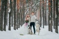 Beautiful bride and groom with two siberian husky are posed on background of snowy forest. Artwork Royalty Free Stock Photo