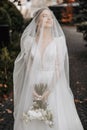 A beautiful bride with her eyes closed is standing holding her bouquet. Royalty Free Stock Photo