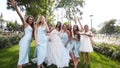 Beautiful bride and her pretty bridemaids in same pale blue dresses posing cheering waving hands in a park. Woman with