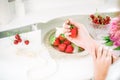 A beautiful bride is holding a strawberry in her hands sitting at a dressing table with a mirror, a bouquet of peonies Royalty Free Stock Photo