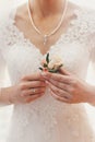 Beautiful bride holding stylish simple boutonniere in hands in b Royalty Free Stock Photo