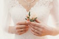 Beautiful bride holding stylish simple boutonniere in hands in b Royalty Free Stock Photo