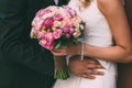 The Beautiful bride holds a wedding bouquet with pink roses and peonies. Groom embrace woman by the waist. Royalty Free Stock Photo