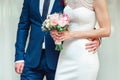 The Beautiful bride holds a wedding bouquet with pink roses and peonies. Groom embrace woman by the waist. Royalty Free Stock Photo