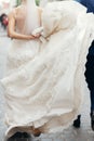 Beautiful bride lifting her dress while on a walk outdoors, gorgeous stylish bride holding white wedding dress close-up