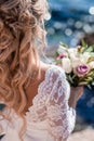 Beautiful bride in luxury wedding dress with bouquet at the sea side. Wedding by the sea. Royalty Free Stock Photo