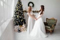 Beautiful bride in luxury wedding dress and pretty bridesmaid in dresse in decorated christmas studio. weddind in Christmas